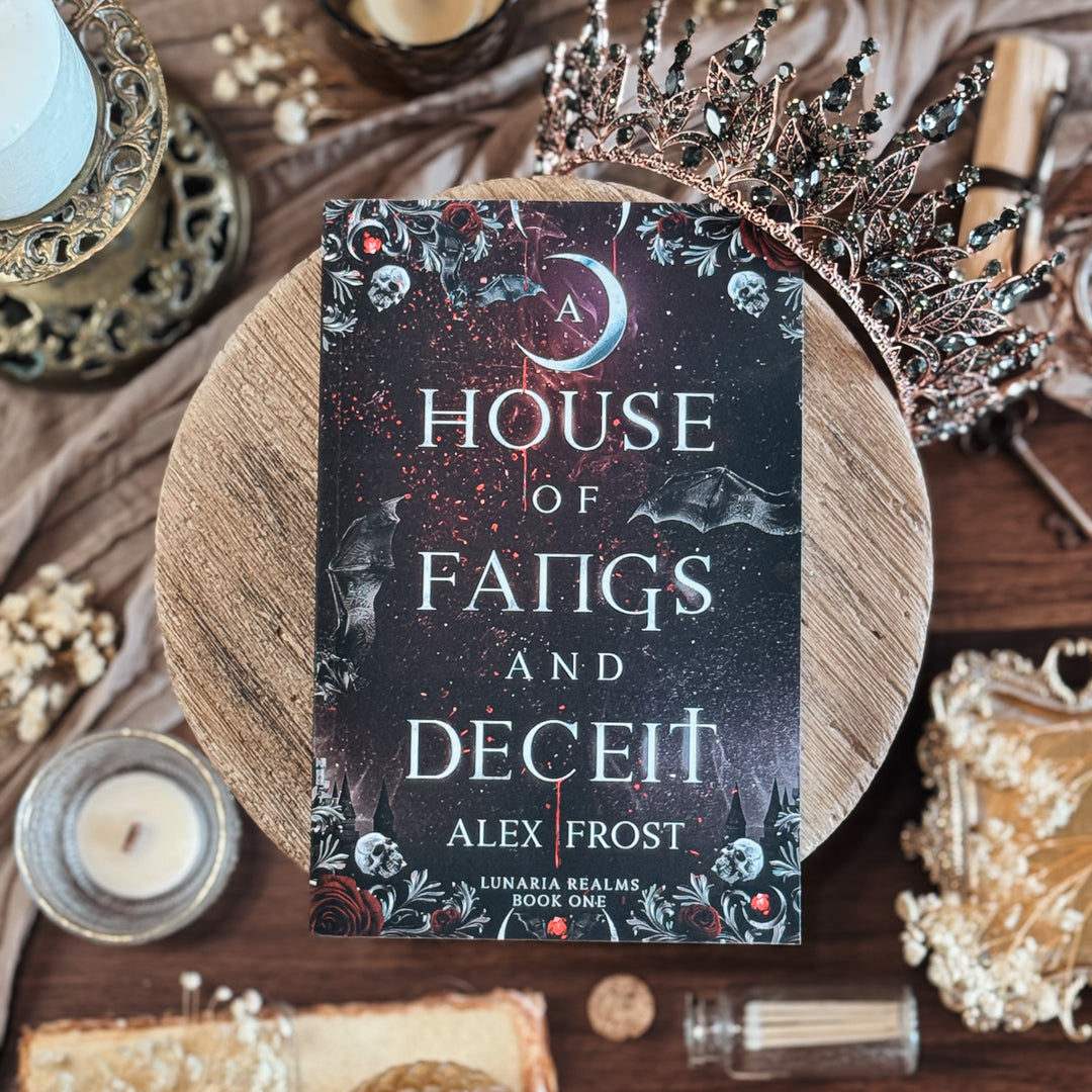 Book titled 'A House of Fangs and Deceit' by Alex Frost on a decorative background with candles and a crown.