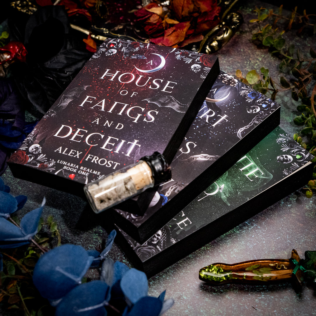 Stack of books titled 'A House of Fangs and Deceit' by Alex Frost on a dark surface with decorative elements.