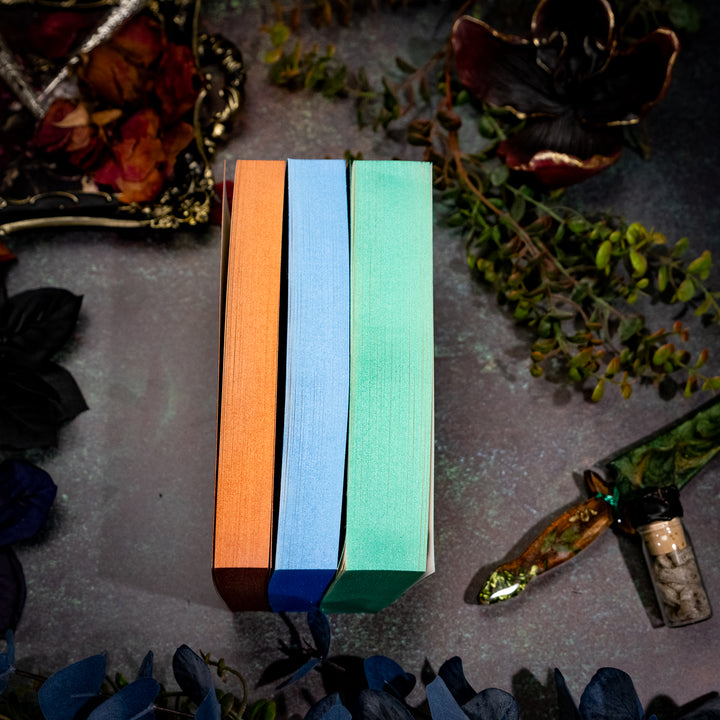 Three wooden bookmarks in red, blue, and green on a textured surface with decorative elements.