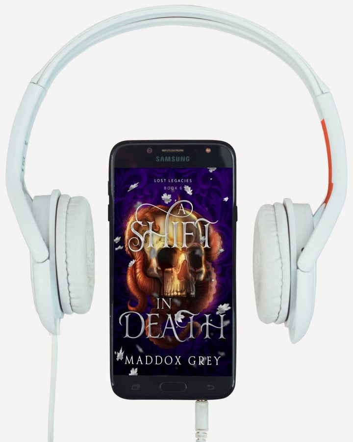 Phone displaying a book cover with a skull and text, surrounded by white headphones.