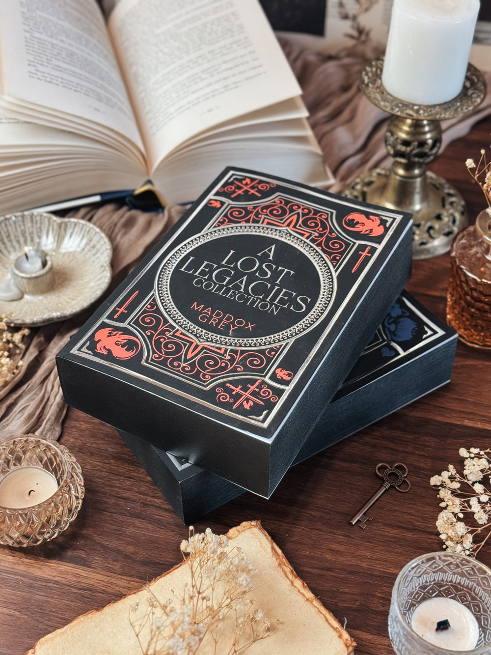 Decorative box labeled 'A Lost Legacies Collection' on a table with candles and books.